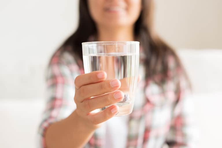 Woman holding out glass of water.