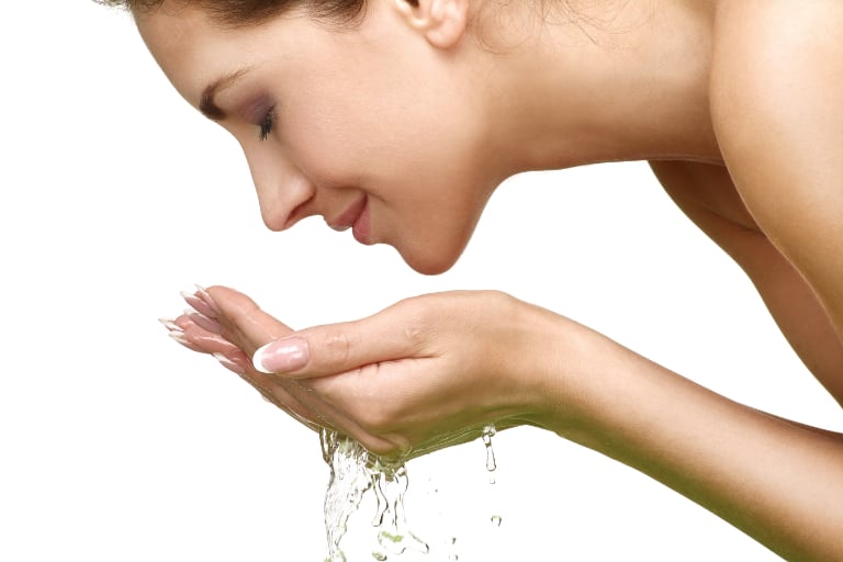 Woman refreshing face with clean water.